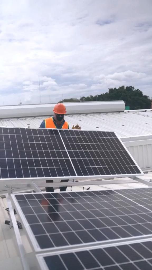 Técnico a instalar painel solar no telhado com equipamento de proteção